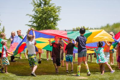 Kids playing with parachute outside of the PACE Center in Parker, CO.