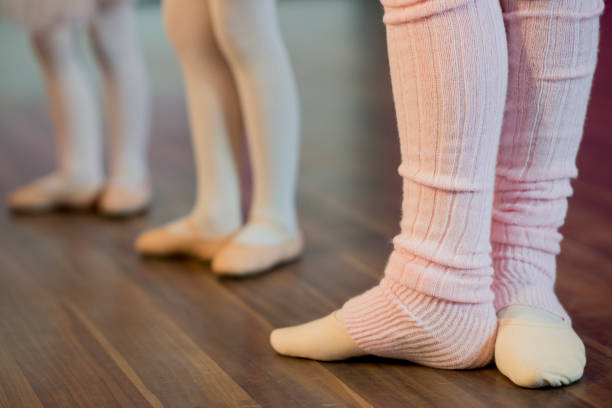 A close up shot of three girls standing in a row during ballet class.