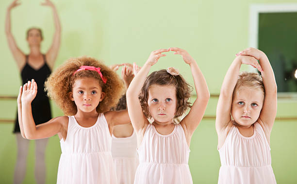 Little girls (4 years) in dance studio taking ballet lesson.  Main focus on girl in middle.