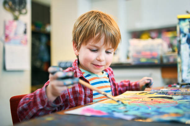 Cute happy little boy, adorable preschooler, painting in a sunny art studio. Young artist at work.
