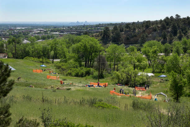 background, members of the public, volunteers and archaeologists dig at the Magic Mountain Archaeological Site in Golden where Native American artifacts have been dated to over 9,000 years old in the Colorado foothills of the Rocky Mountain Front Range.