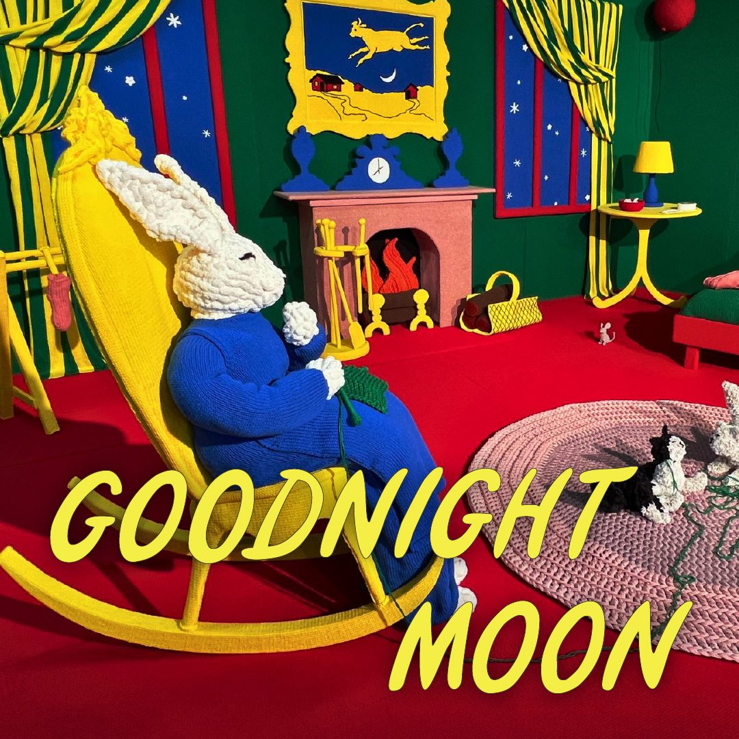The children's book "Goodnight Moon" scene of a bunny in a rocking chair resting by a fireplace, recreated entirely in yarn.