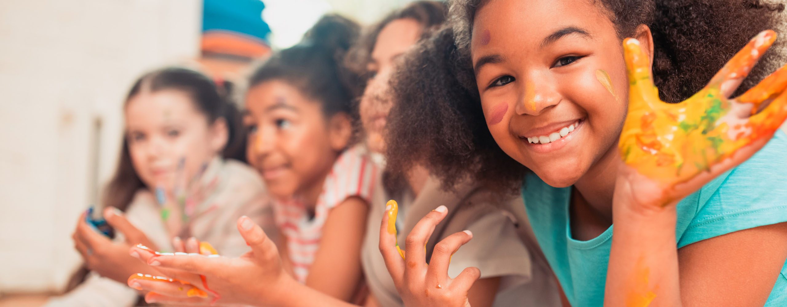 Smiling group of children working together on art project, with paint on their hands